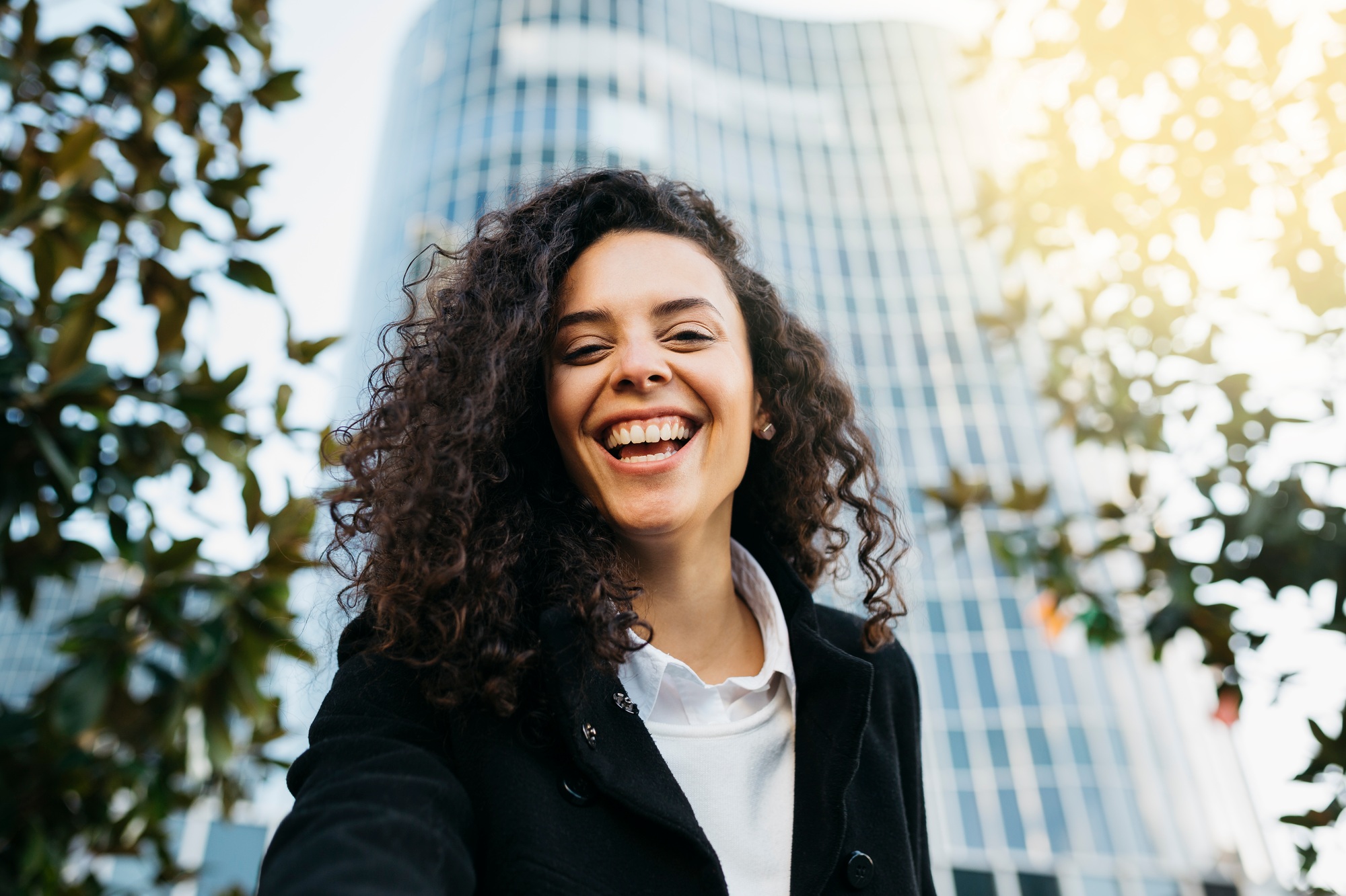 Happy businesswoman smiling in modern city with skyscraper