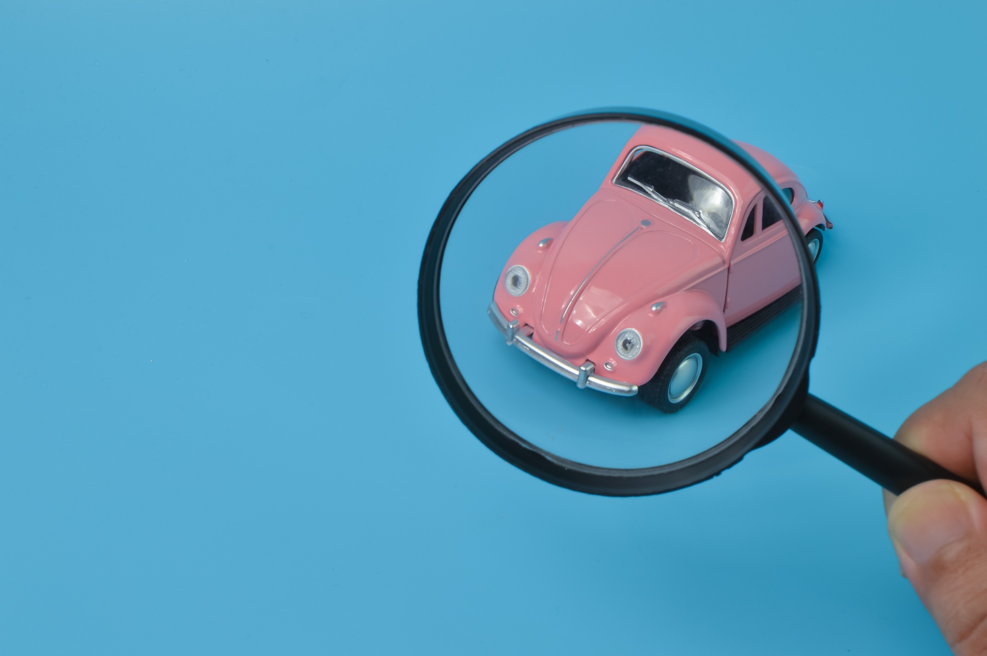 Pink retro car model and magnifying glass. Find a car and car search concept